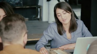 Karışık yarış ekibi modern ofisinde çalışıyor. Genç yaratıcı iş takım projesi, dizüstü bilgisayar kullanarak kadın tartışıyor.