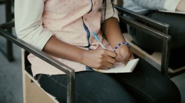 Yakın çekim görünümünü Afrika eller. Bir sandalyede oturuyor ve not defterinde yazılı bir kadın. Öğrenci kıza bir ders.