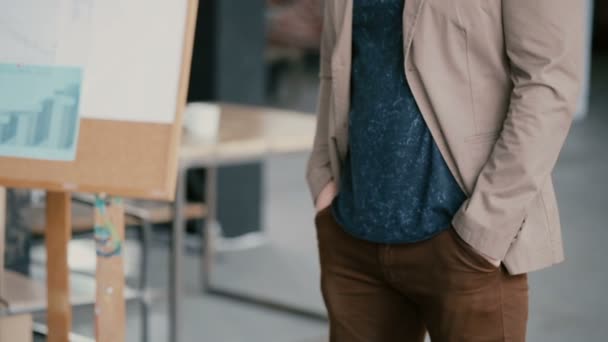 Vue rapprochée du mâle debout dans le bureau du grenier léger et présentation du projet. L'homme garde les mains dans les poches . — Video