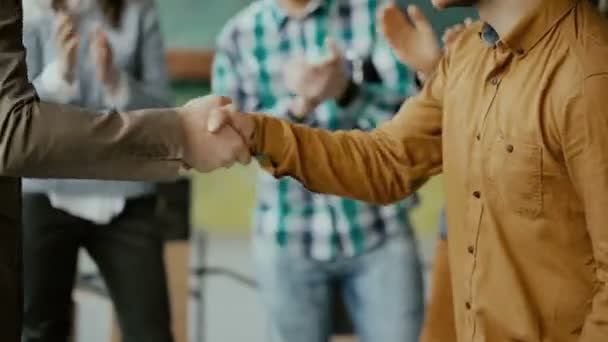 Geschäftsmann schüttelt dem neuen männlichen Mitarbeiter die Hand, klopft ihm auf die Schulter. Gruppe von Menschen, die auf einem Hintergrund klatschen. — Stockvideo