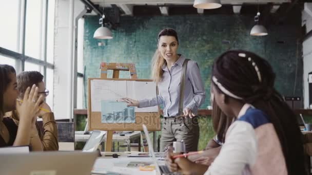 Besprechung eines kreativen Geschäftsteams im modernen Büro. Managerin stellt Finanzdaten vor, motiviert Team zur Arbeit. — Stockvideo