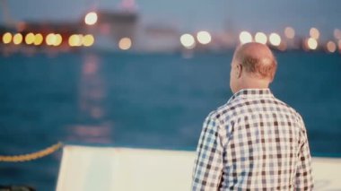 Litvanya, Klaipeda 30 Ağustos 2014. Orta yaşlı bir adam ekose gömlekli limanda akşamları rıhtımdan arıyor.