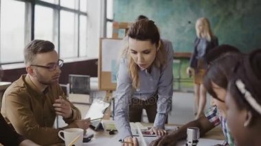 Masanın ayakta ve genç yaratıcı ekibi yön veren kadın takım lideri. Çok ırklı grup beyin fırtınası.