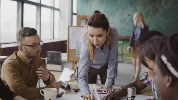 Vedoucí ženského týmu stojící vedle stolu a dává směr mladý kreativní tým. Debata mnohonárodnostní skupiny. — Stock video