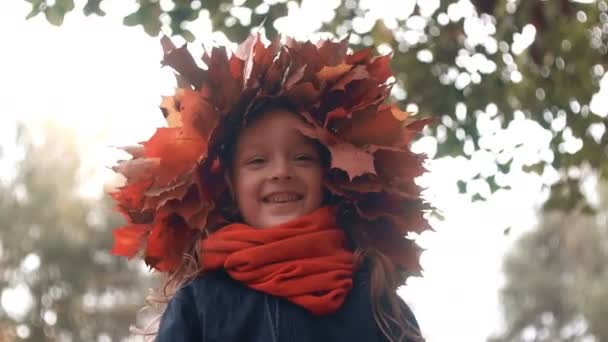 4k close-up retrato de feliz sorrindo linda menina bonito em uma coroa de coroa de flores de folhas de bordo de outono — Vídeo de Stock