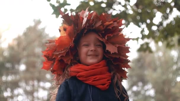 4k close-up retrato de feliz sorrindo linda menina bonito em uma coroa de coroa de flores de folhas de bordo de outono — Vídeo de Stock