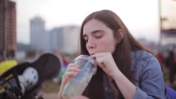 Duas raparigas e irmãs mais novas e um irmão a descansar no parque. Jovem bela senhora com sardas bebendo . — Vídeo de Stock