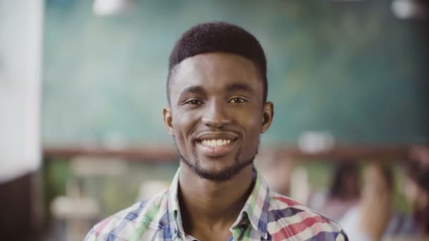 Retrato de jovem empresário africano bem sucedido em um escritório ocupado. Bonito macho olhando para a câmera e começar a sorrir . — Vídeo de Stock