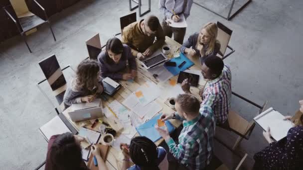 Reunión de negocios en el loft espacio compartido. Equipo multiétnico hablando, mujer gerente dando dirección a la gente. Vista superior . — Vídeo de stock