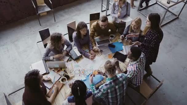 Vista superior del grupo de personas de raza mixta sentados en la mesa, hablando y luego empezar a aplaudir juntos. Reunión de negocios . — Vídeos de Stock