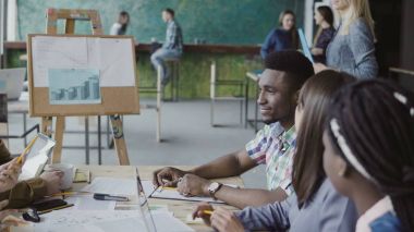 Kadın sarışın Yöneticisi genç iş ekibine geliyor. Çok ırklı bir grup insan trendy hipster ofiste Toplantı.