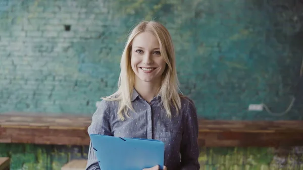Портрет успешной красивой блондинки-предпринимательницы в лофт-коворкинге. Женщина держит документ, улыбаясь . — стоковое фото
