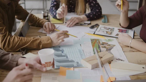 Equipo creativo joven que trabaja en el proyecto arquitectónico. Grupo de personas de raza mixta sentadas a la mesa y discutiendo . — Foto de Stock