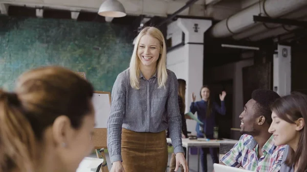 Hermosa mujer rubia gerente dando dirección al equipo multiétnico. Reunión de negocios creativa en la moderna oficina hipster . — Foto de Stock