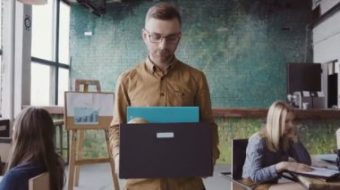 İşten kovulmak yakışıklı delikanlı. Üzgün erkek kişisel eşyalarını kutusuyla taşıyan office yürüyor.