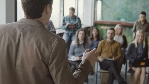 Vue rapprochée du jeune homme d'affaires qui prend la parole lors d'un séminaire au bureau moderne. Mixte groupe de personnes à l'écoute du mâle .