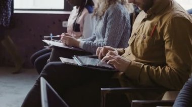Genç çok ırklı takım görünümünü yakın çekim iş toplantısında otur. Erkek ve kadın tablet ve defter üzerinde notlar.