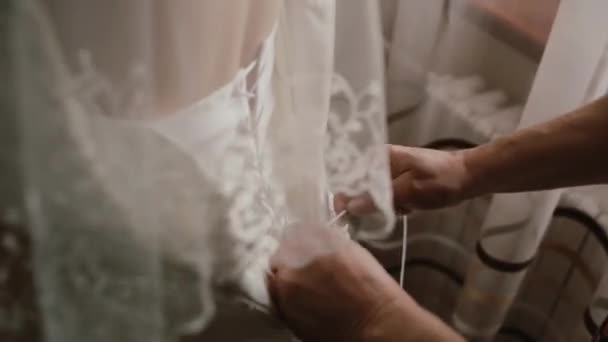 Vue rapprochée de la main féminine aidant la mariée à mettre sur la robe. Mère laçage robe de mariée pour sa fille. Vue arrière — Video