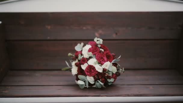 Mooie elegante boeket liggend op de Bank in het park. Verse bloemen samenstelling op de houten achtergrond. — Stockvideo