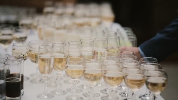 Много бокалов шампанского на столе, человек в костюме принимает одну порцию алкоголя. Деловая встреча класса люкс . — стоковое видео