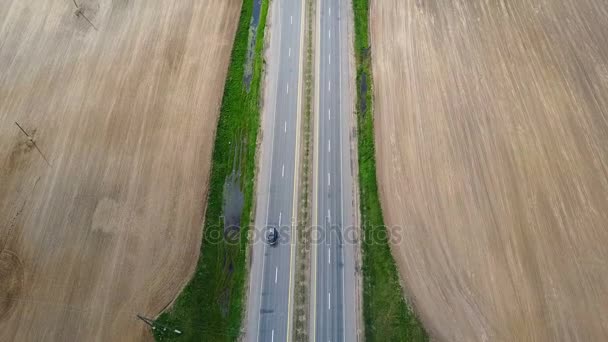 Letecká dron záběr prázdná dálnice. Auto přes silnici na venkově prostřednictvím pole. — Stock video