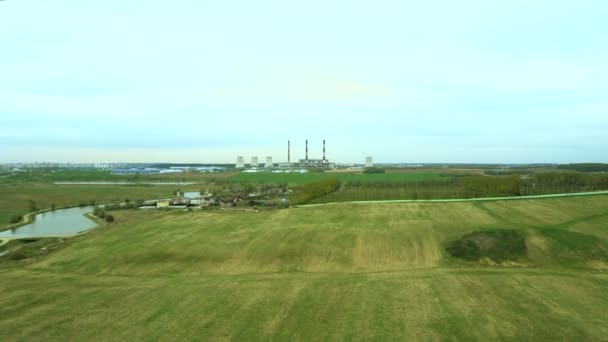 Vista aérea del campo verde y la fábrica industrial. Vuelo sobre la planta produciendo energía térmica con tuberías . — Vídeo de stock