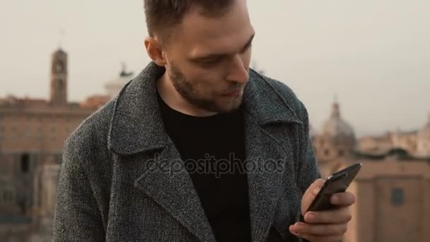 Portrait de jeune homme beau utiliser le smartphone à l'extérieur. Homme d'affaires attrayant utiliser le gadget comme bureau mobile . — Video