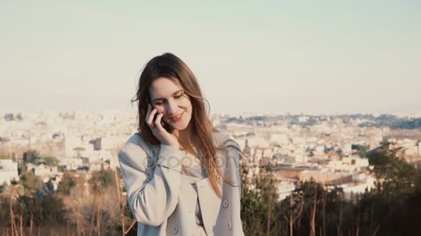 Портрет молодой красивой женщины, стоящей на панораме Рима, Италия. Женщина разговаривает на смартфоне . — стоковое видео