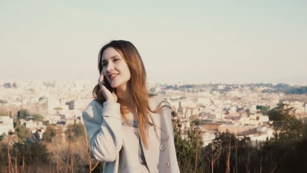 Jonge aantrekkelijke vrouw praten over de smartphone, glimlachend. Gelukkig toeristische vrouw genieten van de stad. Rome, Italië. — Stockvideo