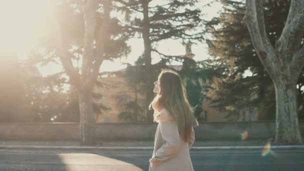 走在公园附近的道路在日落时分年轻漂亮的女人。女性享受明媚的春光的一天，探索城市. — 图库视频影像