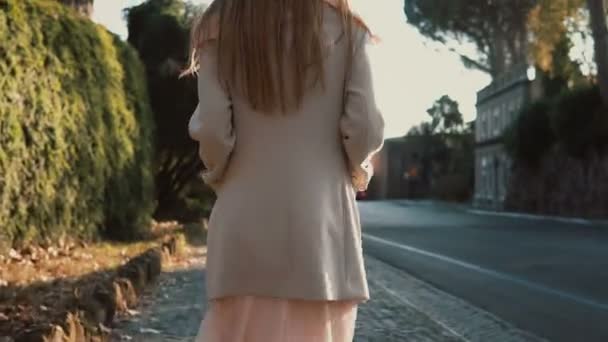 Glückliche junge Frau, die an einem strahlenden Frühlingstag im Park spazieren geht. verträumtes Mädchen erkundet die Stadt und genießt das Wetter. — Stockvideo