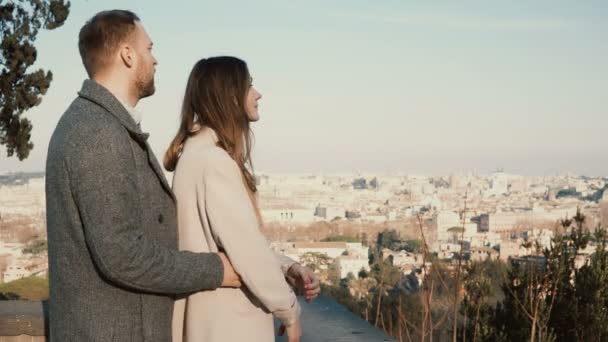 Cita romántica de pareja joven. El hombre viene a la mujer por la espalda y la abraza. Mirada masculina y femenina a Roma, Italia . — Vídeos de Stock