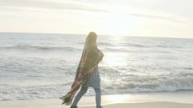 Deniz kıyısında yürüyen genç kadın. Yalnız sahilde rüzgarlı soğuk günde vakit ekose olan dalgın dişi.