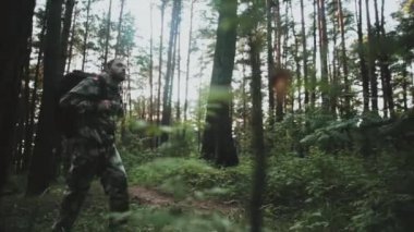 Genç forester doğa parkı ile yürüyüş ve etrafa sırt çantası ile. Adam haki üniforma içinde keşfetmek bölge.
