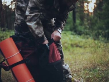 Yakın çekim ormanda çayır üzerinde sırt çantası ambalaj adam görünümünü. Erkek kamuflaj yalnız doğada yürüyüş içinde.
