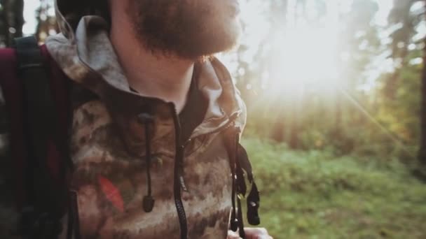 Vue rapprochée de l'homme barbu debout dans la forêt le matin. Homme en camouflage avec sac à dos à la nature . — Video