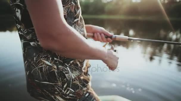 Närbild av manliga händer som håller fiskespö med snurrande hjul. Ung man fånga fisken ensam. — Stockvideo