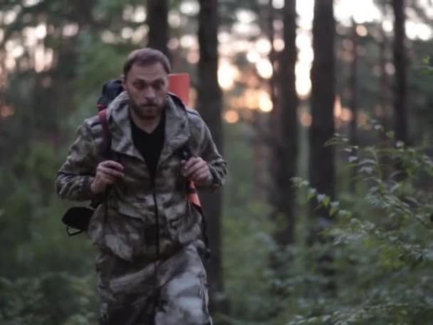 Giovane turista con zaino in camuffamento unionalls passeggiando attraverso la foresta. Maschio è impegnato in orienteering . — Video Stock