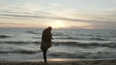 Adam akşam sahilde çalışır ve kum atar. Dalgalar ile deniz kıyısında doğa manzara zevk erkek.