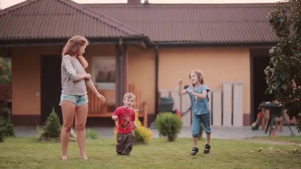 Little brother and sister repeating after elder sister. Family dancing on the backyard outside on the summer day. — Stock Video