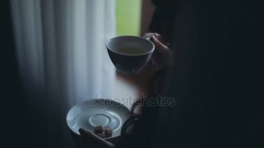 Mesafe içine bakarak ve çay içme esmer kadın görmek. Sabah evde tek başına harcama erkek.