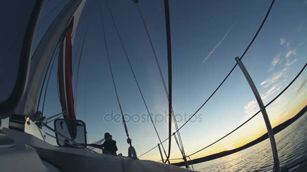 Jacht, die bei Sonnenuntergang im Wind segelt. schöne Brautpaar, Braut und Bräutigam verbringen Zeit im offenen Wasser. — Stockvideo