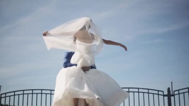 Happy groom hold on hands his bride in white wedding dress and turning around. Newlyweds enjoy sunny day. Slow motion. — Stock Video