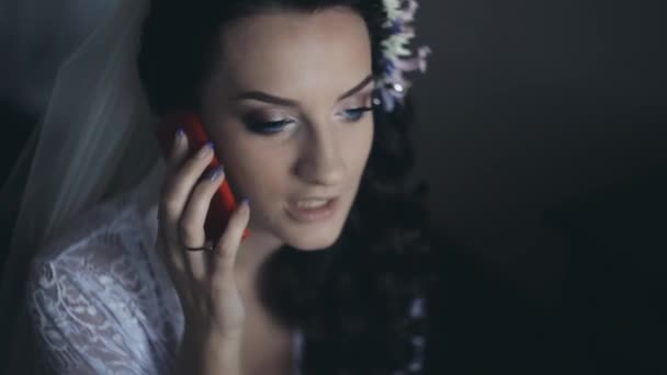 Portrait de mariée parlant sur smartphone tandis que le maquilleur prépare la femme à la cérémonie de mariage, en utilisant un pinceau .