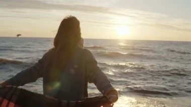 Arkadan Görünüm olan gergin silah ile rüzgarlı sahilde güneşin tadını ekose genç kadın. Özgürlük kavramı.