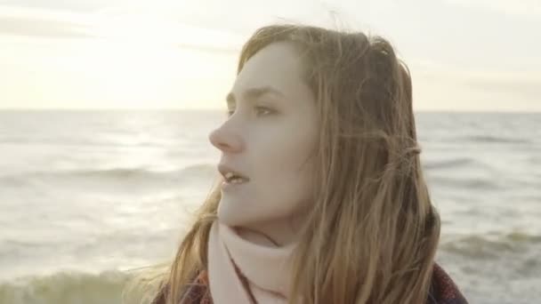 Retrato da jovem mulher bonita olhando para a distância na costa do mar. Feminino em pé na praia no dia frio . — Vídeo de Stock