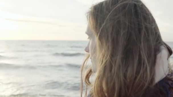 Portrait of young attractive female standing on the shore of the sea with plaid, looking into the distance and thinking. — Stock Video