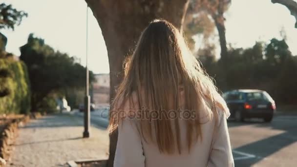 Hátulnézet a fiatal nő egyedül sétálni a belvárosban. Töprengő nő megy az út mellett, a ragyogó napsütéses napon. — Stock videók