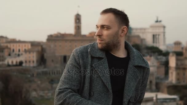 Joven hombre guapo de pie en el centro de la ciudad y mirando a su alrededor. Varón serio esperando a alguien y haciendo turismo . — Vídeos de Stock