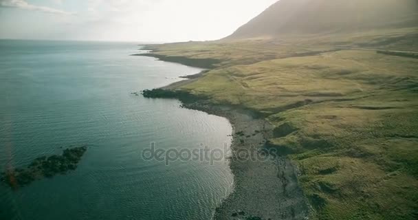 В солнечный день вертолет пролетает по побережью моря в Исландии. Красивый пейзаж лавовых полей и воды . — стоковое видео